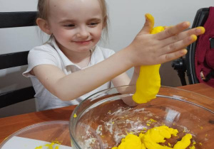 dziewczynka ugniata nad miską żółte ciasto